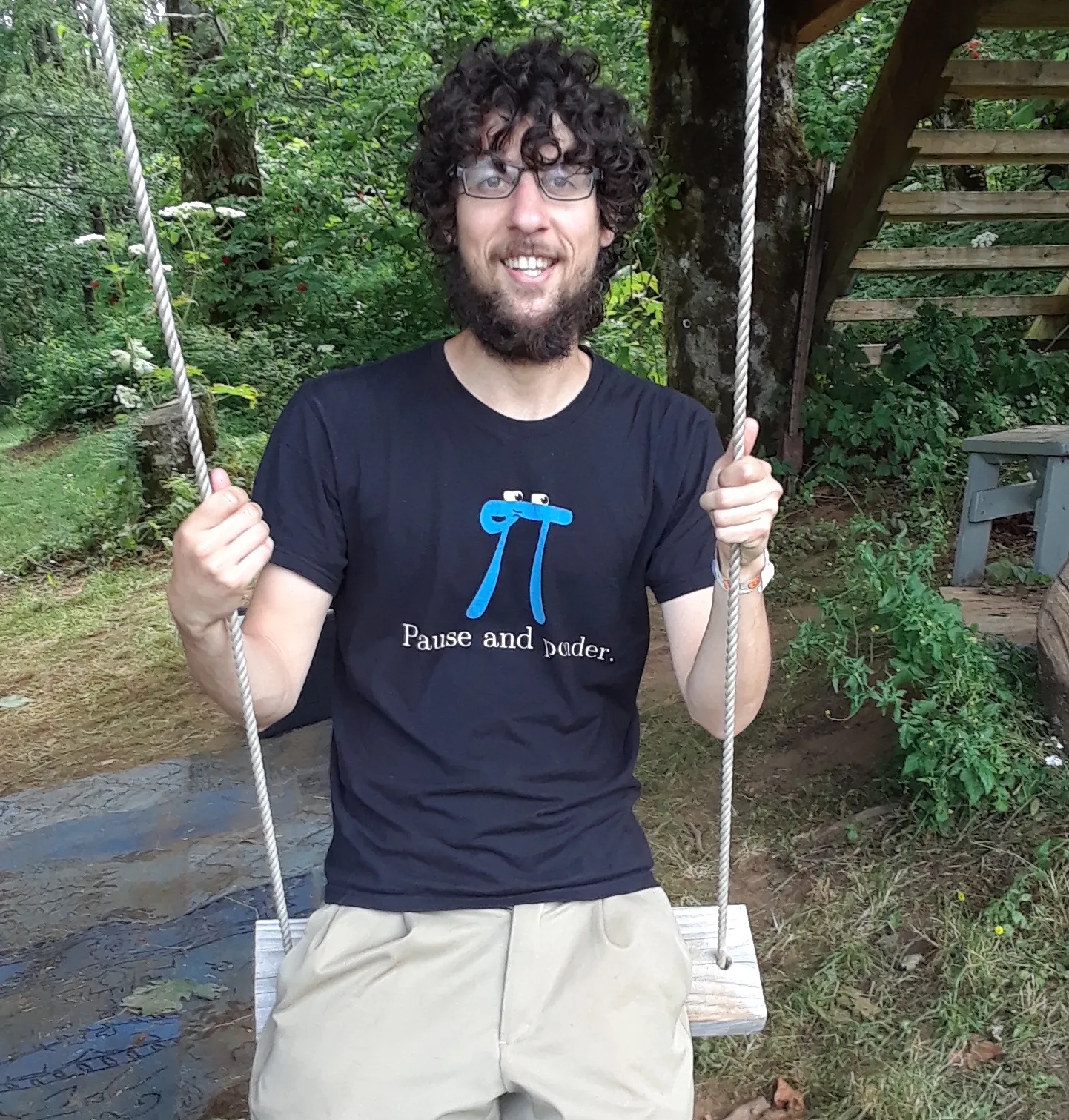Paul Gafni sitting on a garden swing, wearing a shirt with a pi symbol.
